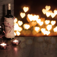 Romantic wine and candles with hearts in the air