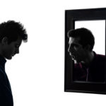 Man in front of his mirror in shadow